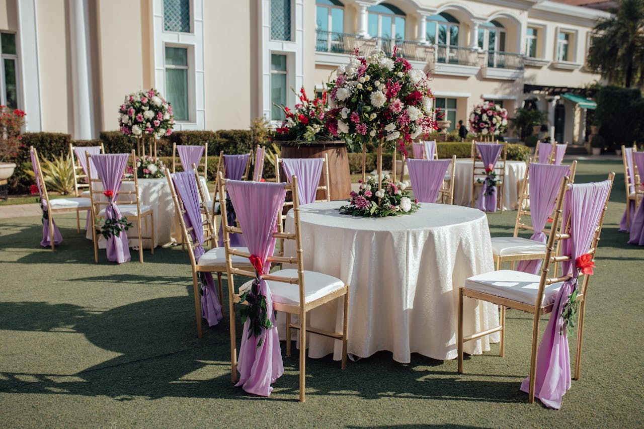Beautiful outdoor wedding reception area with floral arrangements and lavender chairs.